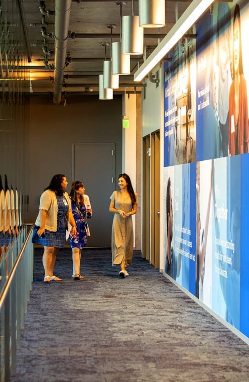 Three people are walking together in a hallway.