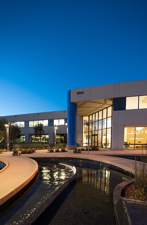 A large building with water landscape lit up at night.