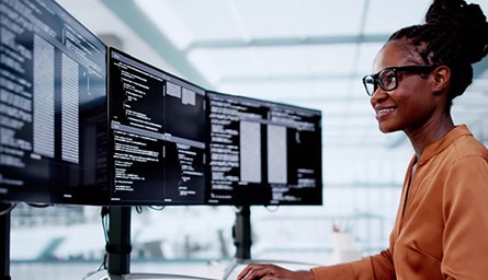 A person is standing in front of a computer monitor.