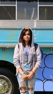 A person standing in front of a bus with a blue shirt.