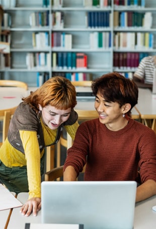 A person and person are looking at a laptop.