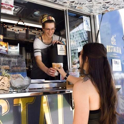 A person standing in a coffee truck serving a customer