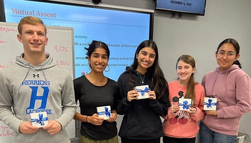 A group of students holding up gift boxes.