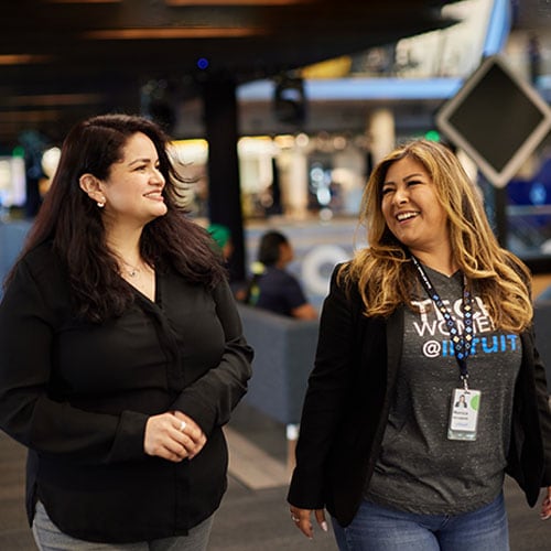 Two people are standing in a terminal with their luggage.