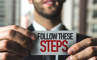 man holding a follow these steps sign