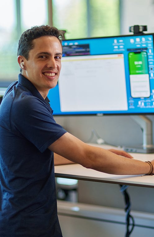 A person in front of a monitor and smiling