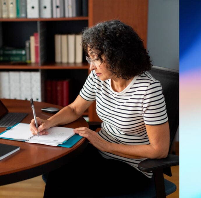 A person sitting at a desk with a notebook and pen.