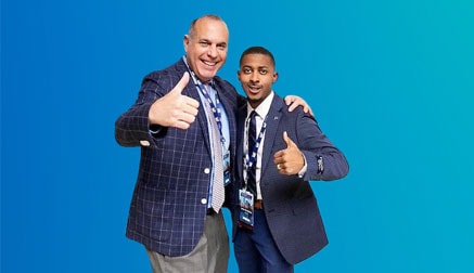 Two men wearing a suit holding a thumbs up