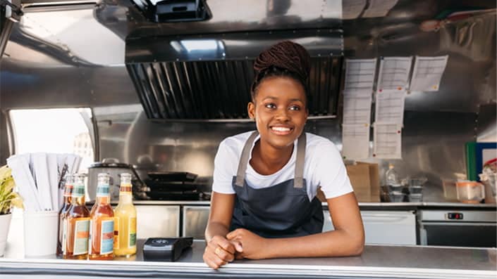 A person smiling while standing in a kitchen.