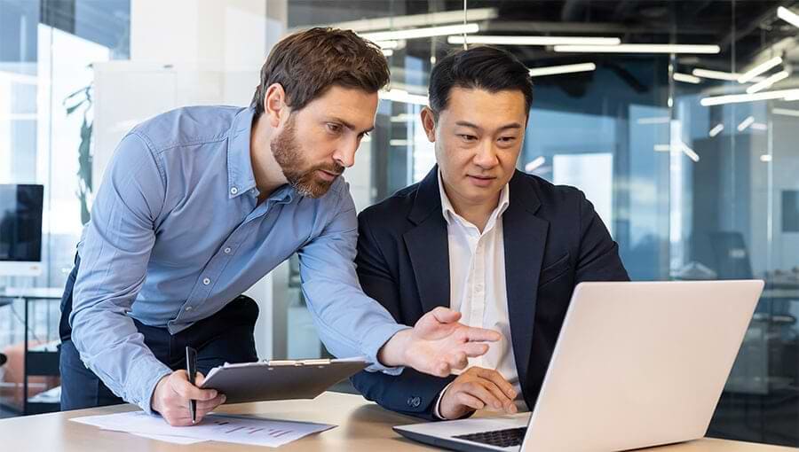 Two businessmen review capital investment analysis documentation.