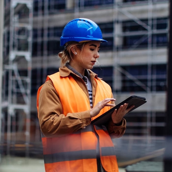 A person in a construction site holding a cell phone.
