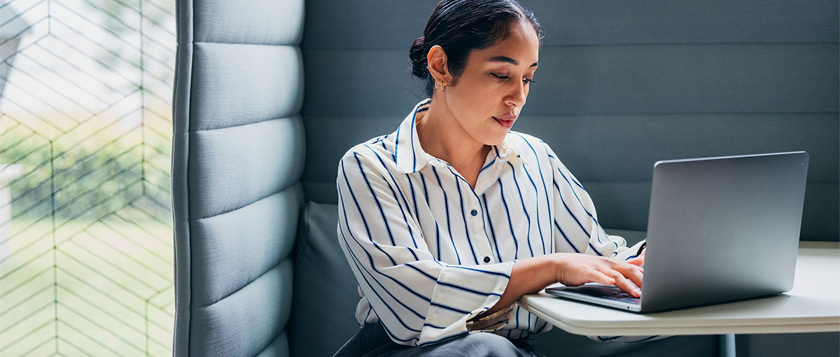 A person sitting on a chair looking at a laptop.