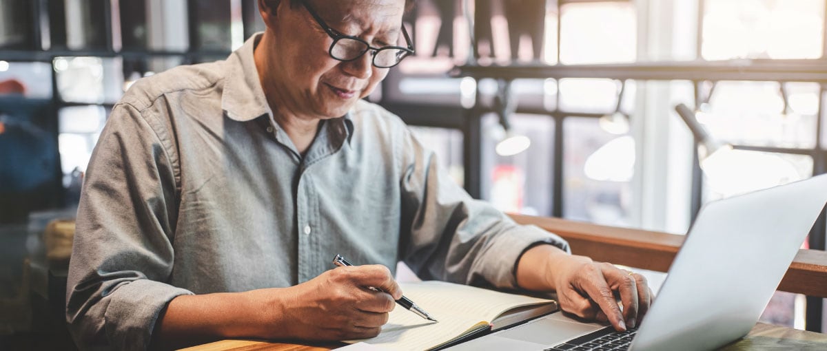 A person sitting at a table with a laptop computer.