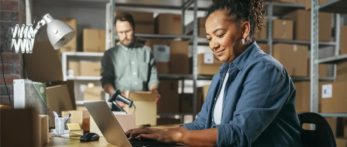 A person in a blue shirt and black tie looking at a laptop.
