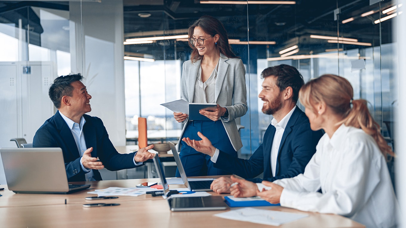 A group of people sitting around a table with laptops sharing Intuit Enterprise Suite updates